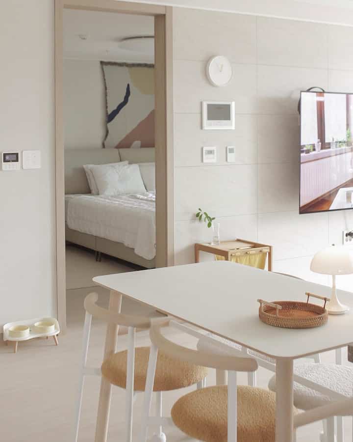 明るいホワイトとベージュのトーンのキッチンダイニング、犬用の食器とミニマルインテリアが調和した空間