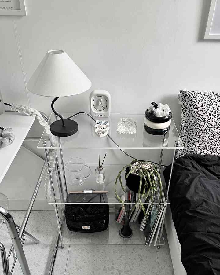 Modern bedroom in white and black tones featuring acrylic console table, table lamp, and patterned cushion in a clean layout