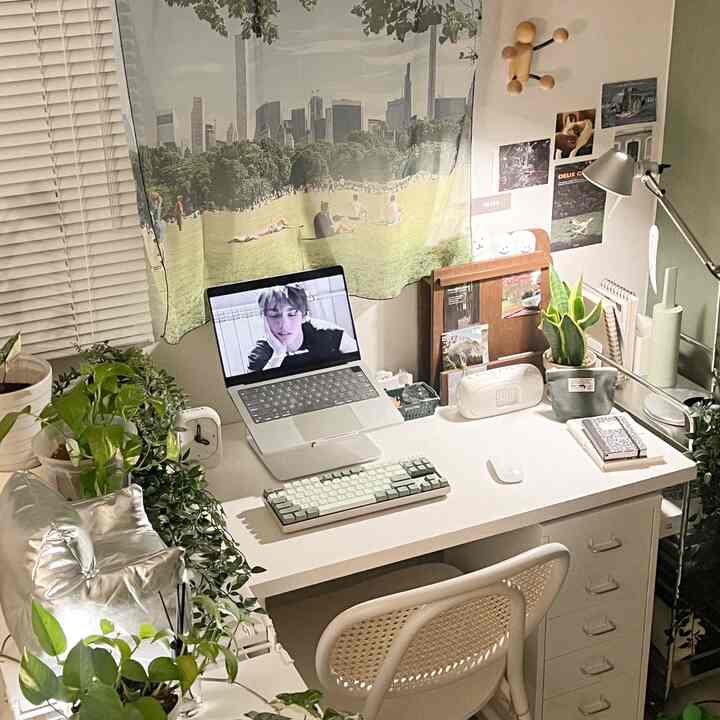 A compact home office space blending white and wood tones, featuring a tidy desk and abundant plants for a comfortable remote work setting