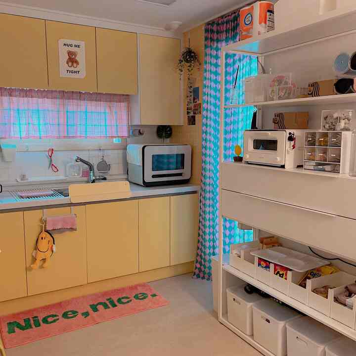 Pastel yellow cabinets and pink and sky blue curtains in a compact kitchen space