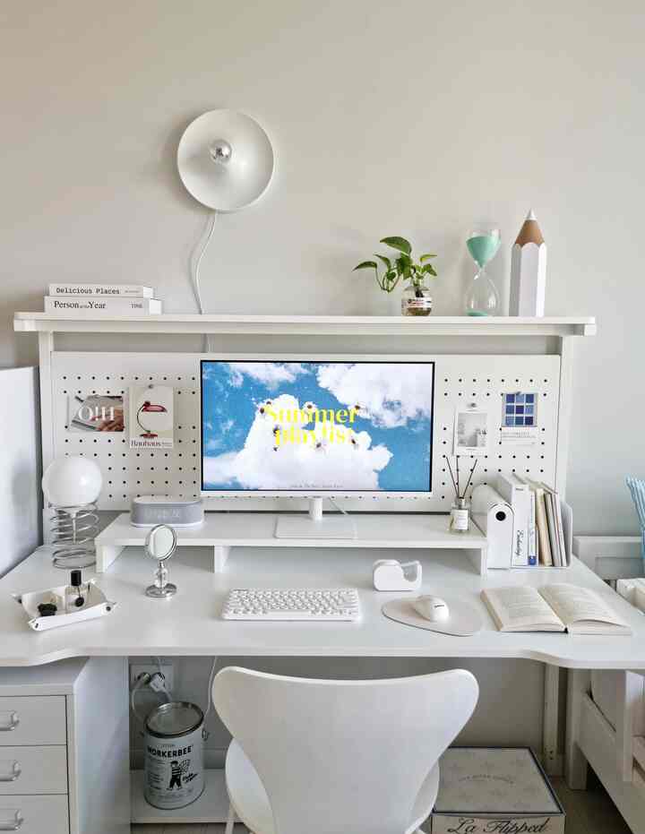 白を基調とした子供部屋のホームオフィス、シンプルで整えられたデスクと壁付け照明、植物やオブジェが配置された雰囲気のあるインテリア