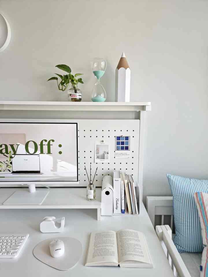 Bright white-toned kids' room desk space featuring a computer monitor, organized bookshelf, and a children's bed with a clean interior
