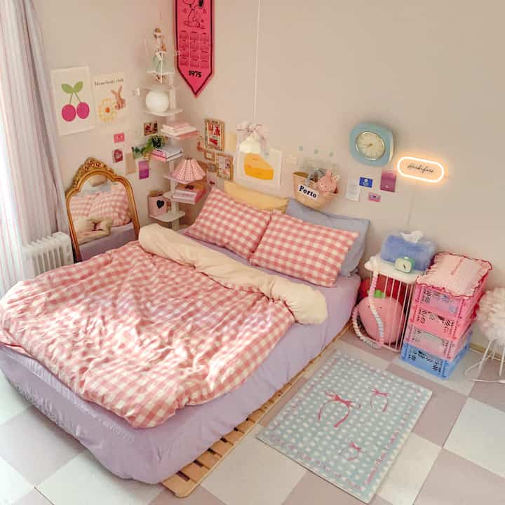 Pink-toned bedroom featuring checkered bedding, wall clock, and storage boxes creating a cozy atmosphere