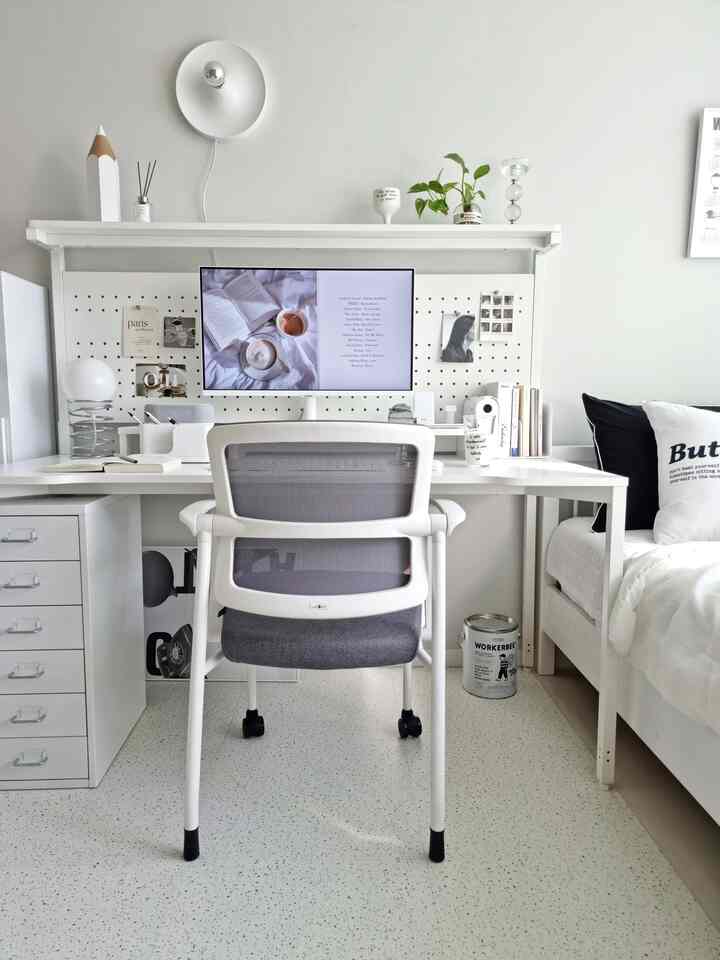 白とグレーのトーンの子供部屋のホームオフィス、デスクとオフィスチェアが配置されたミニマルなインテリア