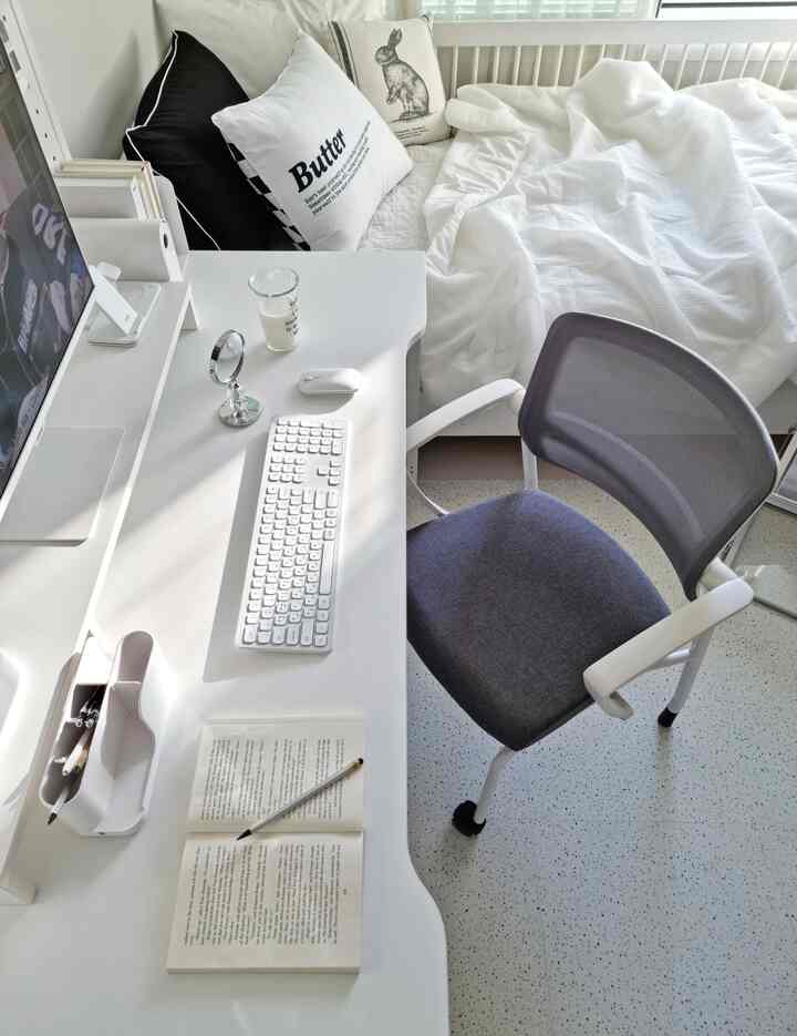 Bright, clean white-toned studio apartment featuring a desk and office chair in a modern remote work setup