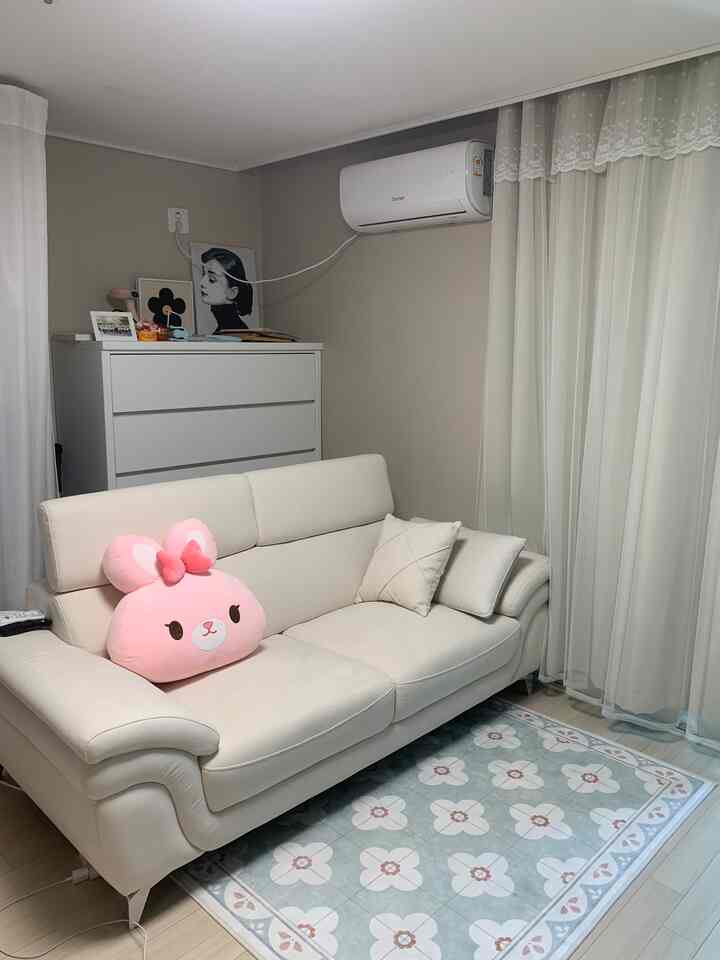 明るいアイボリーとホワイトのトーンのリビング、清潔なレザーソファとミント色の白い花柄ラグが調和したシンプルなインテリア