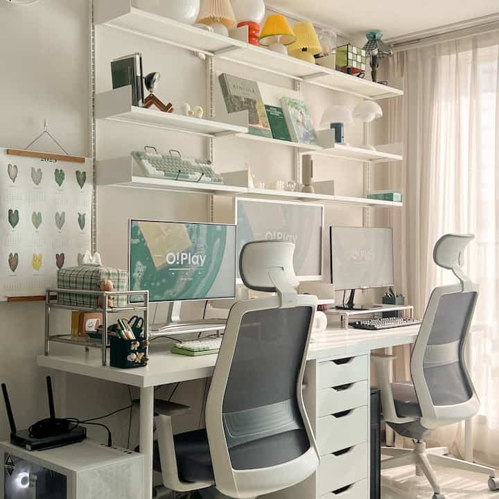White-toned home office space featuring computer desks, chairs, and wall-mounted shelves in a compact room