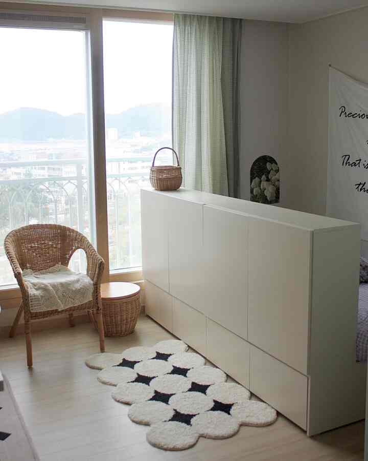 Bright kids' room in white and natural tones featuring a large storage cabinet and rattan chair with cozy atmosphere