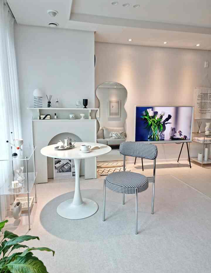 Bright white and silver-toned living room featuring a round table and houndstooth chair in a modern setting