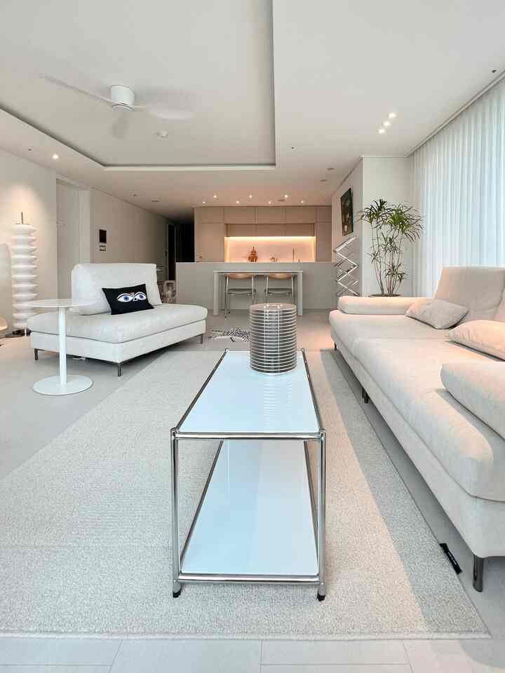 明るいホワイトトーンのリビングとダイニング、シンプルなホワイトのソファとメタリックフレームのコーヒーテーブルが配置されたモダンでナチュラルな空間