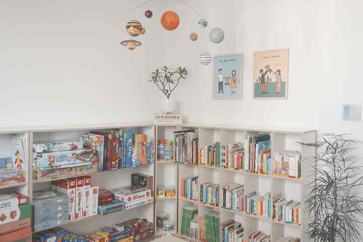 Bright natural-toned kids' room featuring corner bookshelf and storage cabinets for efficient organization