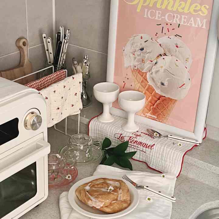 A white and beige toned kitchen space featuring ice cream poster and cozy home cafe accessories creating a warm atmosphere