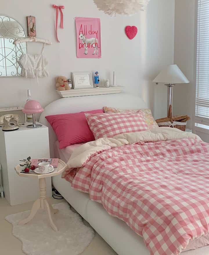 Cozy bedroom featuring pink checkered bedding and white walls with soft lighting atmosphere