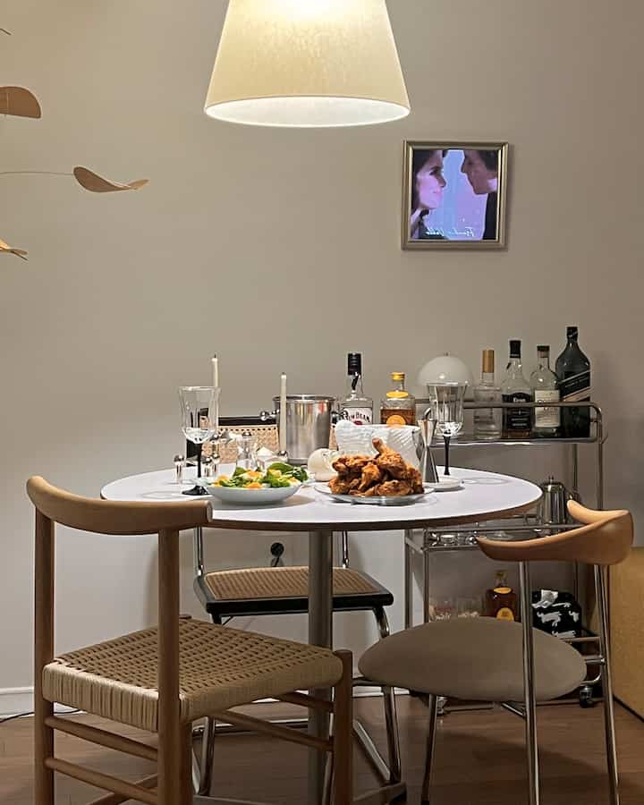 Natural wood dining chairs and white round table set in a modern home bar style dining room