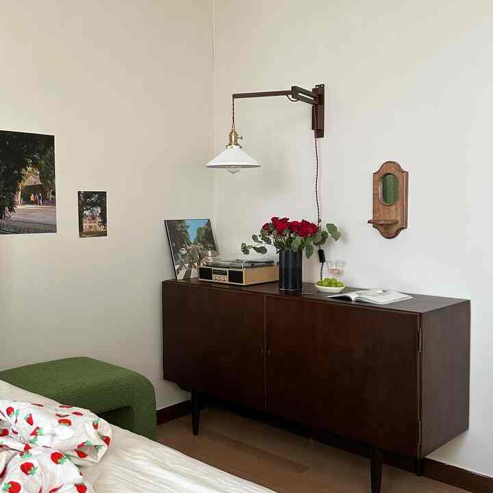 ナチュラルカラーの壁とダークウッドトーンのサイドボードがあるヴィンテージスタイルの照明と小物が配された空間