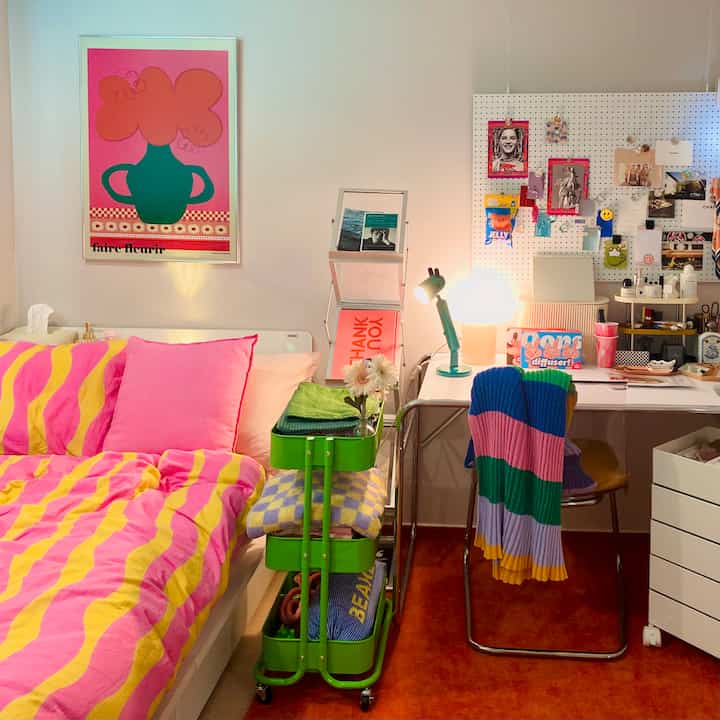 Bright and colorful bedroom with pink and yellow bedding, featuring an IKEA transparent chair and desk lamps in a cozy single household setup