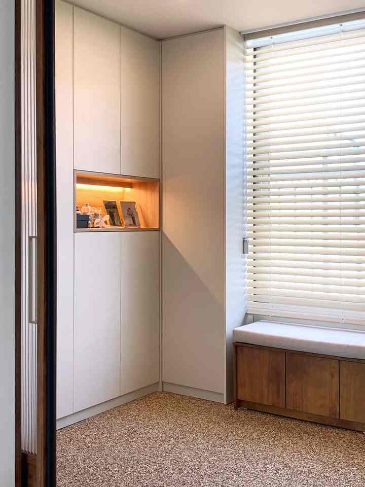 明るいアイボリー色のシューズラックと木製ベンチが配置された印象的な玄関スペース