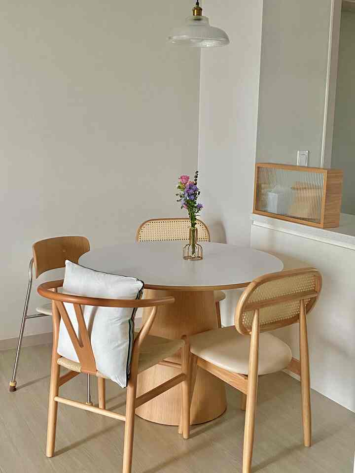 白と木目調のキッチンのダイニングスペース、丸テーブルと自然な木製の椅子が配置された雰囲気のあるインテリア