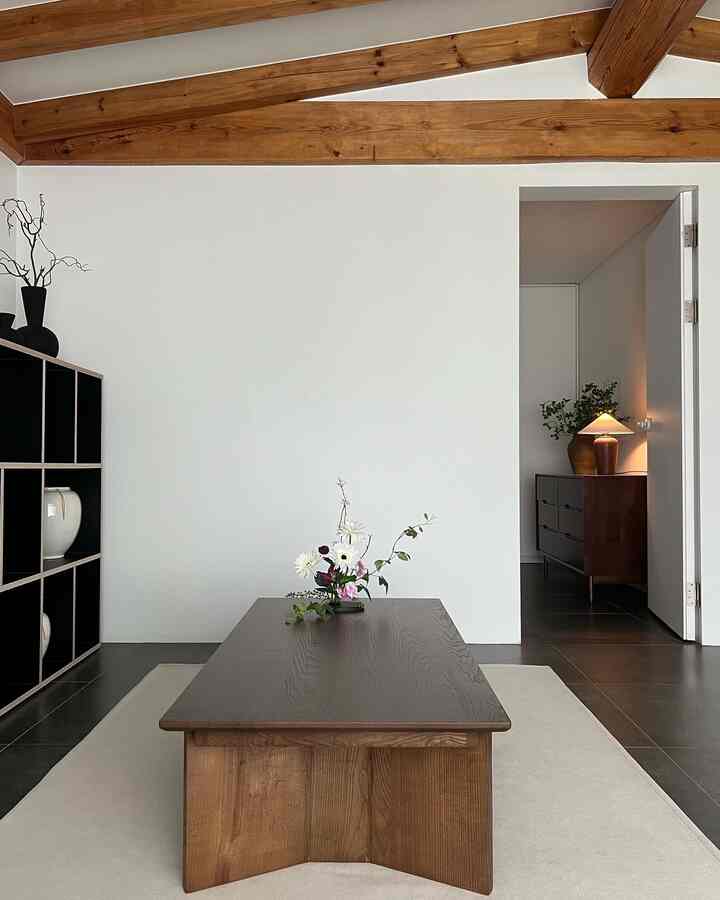 木目調と白を基調としたナチュラルモダンなリビング、シンプルなインテリアに低めの木製テーブルと花の飾り付けが配された空間