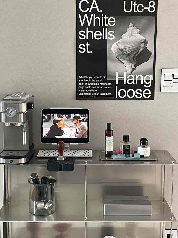 Neutral tone wall with steel shelving, coffee machine, and iPad in a simple modern home cafe space