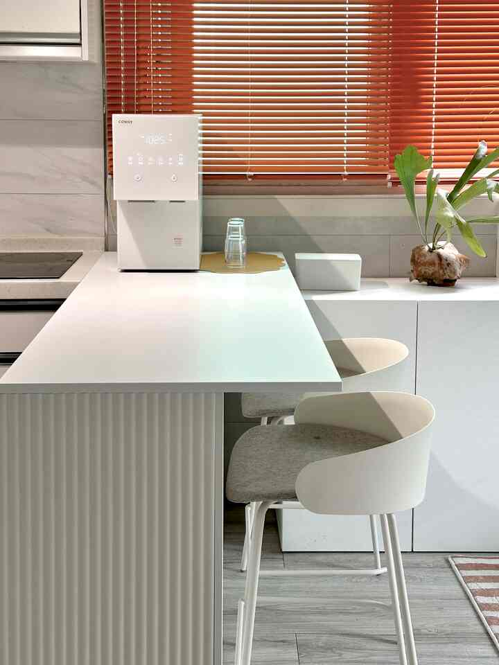 A natural and modern kitchen featuring a white island dining table, dining chairs, and brown blinds