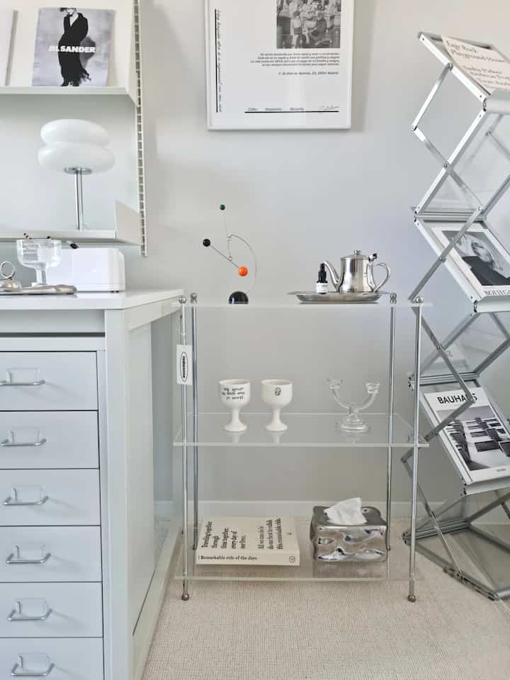 白とモノトーンのモダンな書斎、アクリル棚とミッドセンチュリーモダン家具が配置された印象的なインテリア