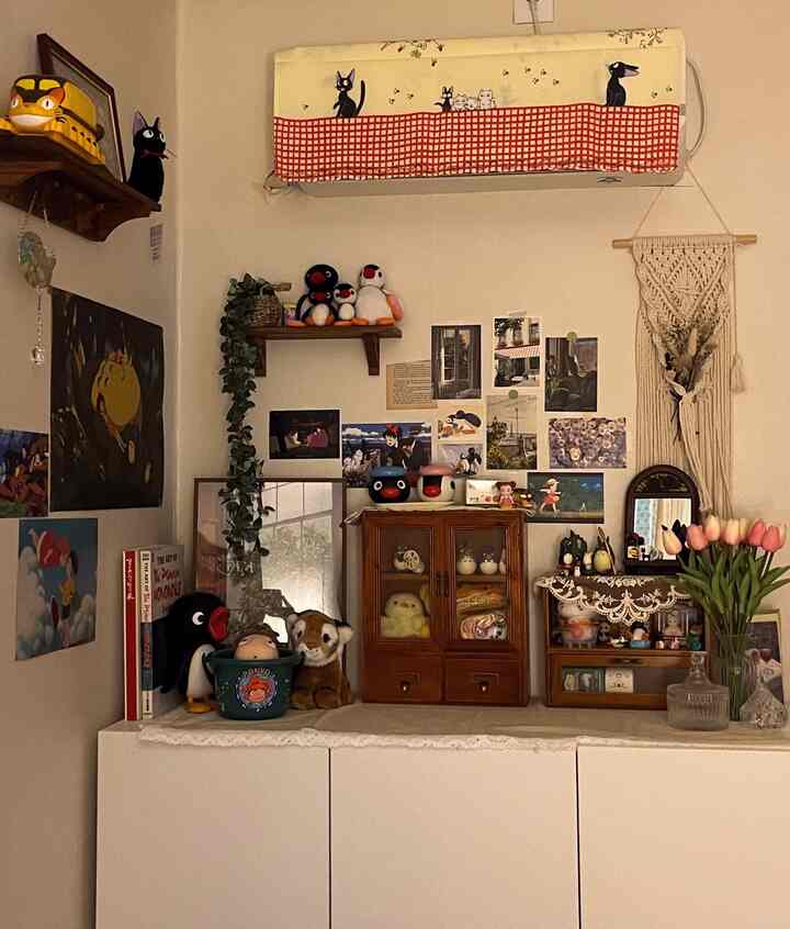 ベージュと木目調のヴィンテージなオブジェ空間、ジブリのキャラクターポスターや額縁、花瓶が配置された雰囲気のあるインテリア
