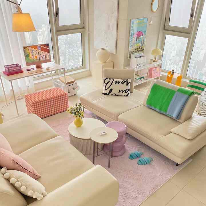 Pastel-toned living room featuring beige leather sofas and a light pink shag rug, creating a cozy atmosphere
