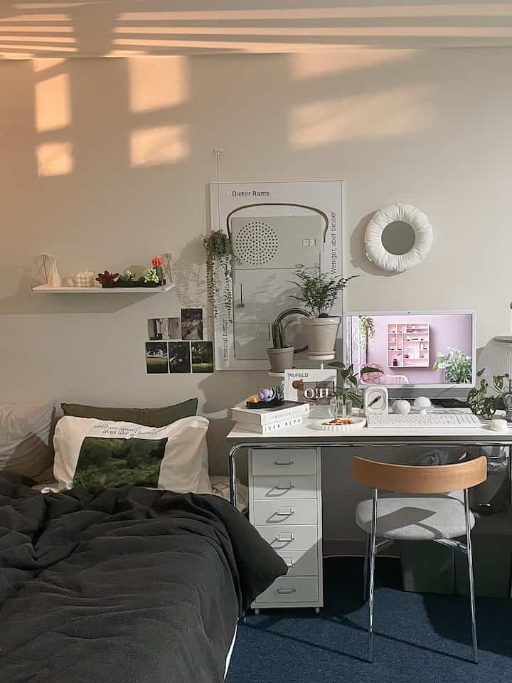 Modern home office bedroom with white walls, black bedding, white desk, and green plants creating a harmonious atmosphere
