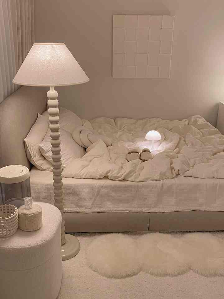 アイボリー調の寝室、ベッドと枕、ワイヤレス照明とフロアランプが配置された落ち着いた印象的な空間