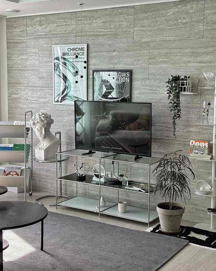 グレーのタイル壁にメタル棚とテレビ、コーヒーテーブルが配置されたミッドセンチュリーモダンのリビング空間