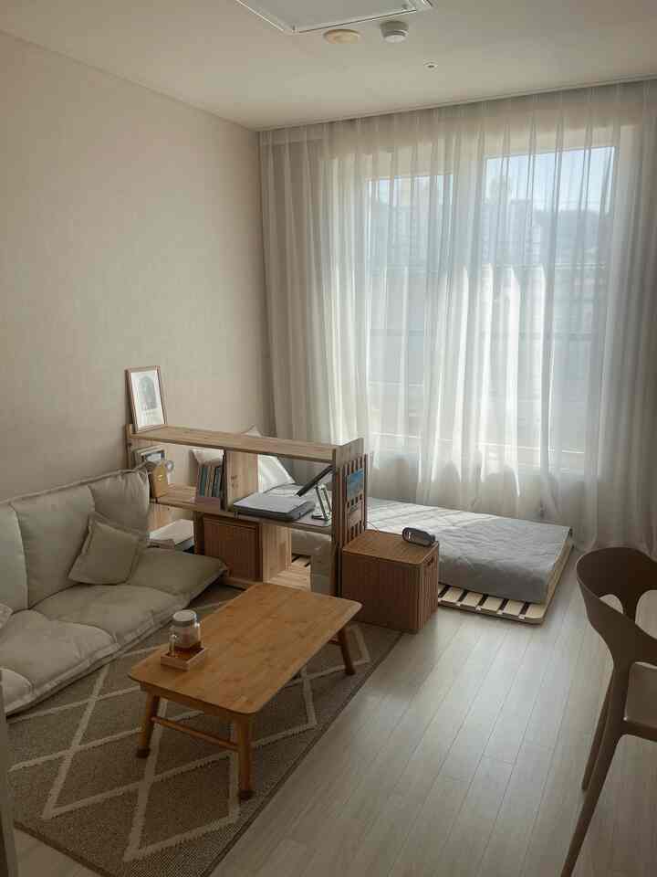 明るいベージュとナチュラルな木目調のリビングと寝室空間、シンプルでコンパクトな家具配置
