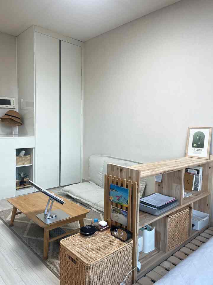 ベージュトーンのワンルームリビング、ナチュラルウッド家具とラタン収納バスケットが配置されたシンプルで落ち着いた空間