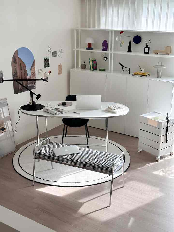 柔らかな白色調のホームオフィス、白いキャビネットと楕円形のデスクがシンプルに配置された清潔感のある書斎インテリア