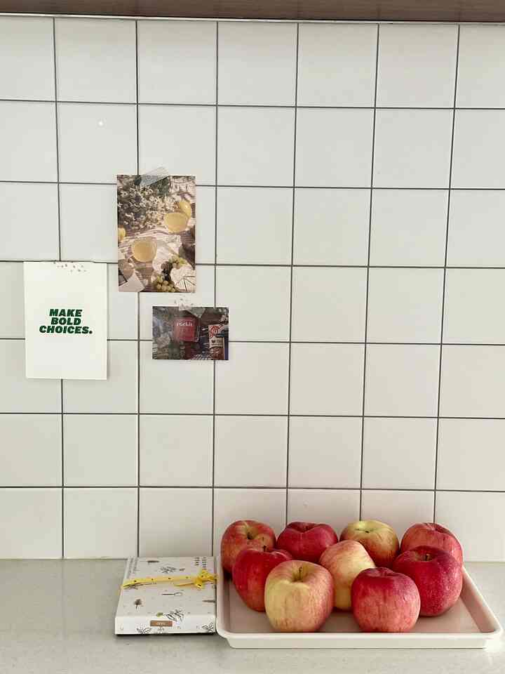 Clean kitchen space with white tiled wall and tray of red apples placed on the countertop
