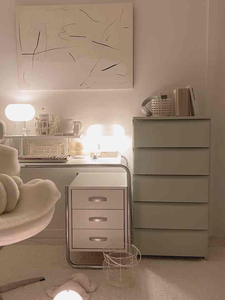 Softly lit white-toned home office space featuring modern dresser and desk with abstract art, creating a clean interior atmosphere