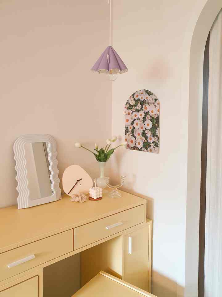ベージュ色調の寝室化粧台、ウェーブミラーと花瓶、キャンドルが配置された印象的でシンプルなインテリア