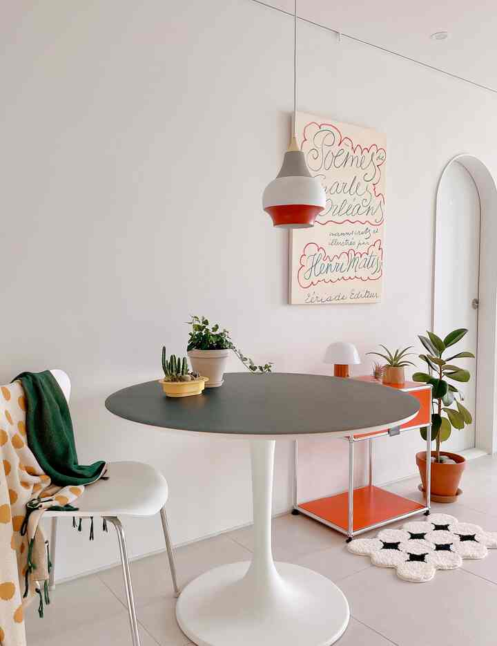 White mid-century modern kitchen featuring round dining table and plants with fresh, modern atmosphere