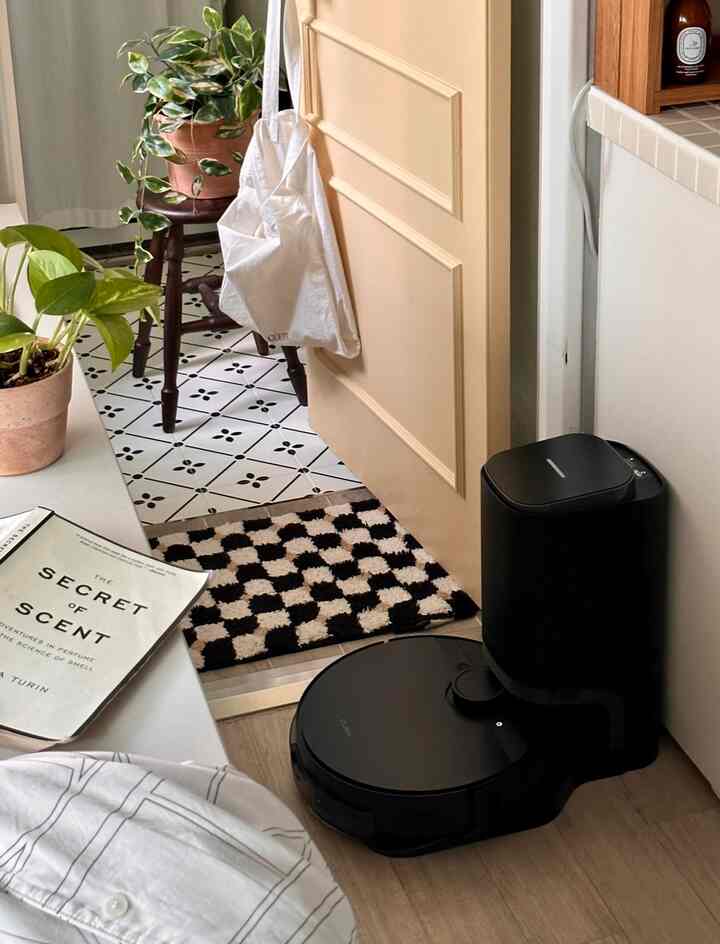 黒と白の色調のキッチン空間、チェッカーボードのラグと植物が配置された清潔感のある玄関インテリア