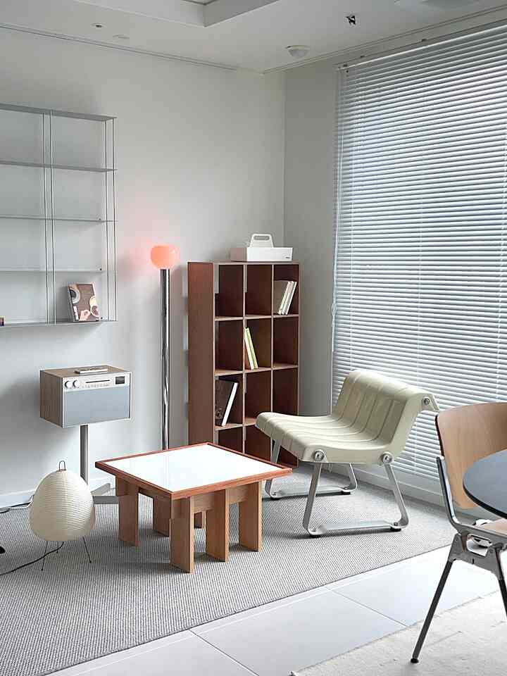 Light-filled living room with white walls, wood furniture, and a sisal rug creating a cozy reading corner