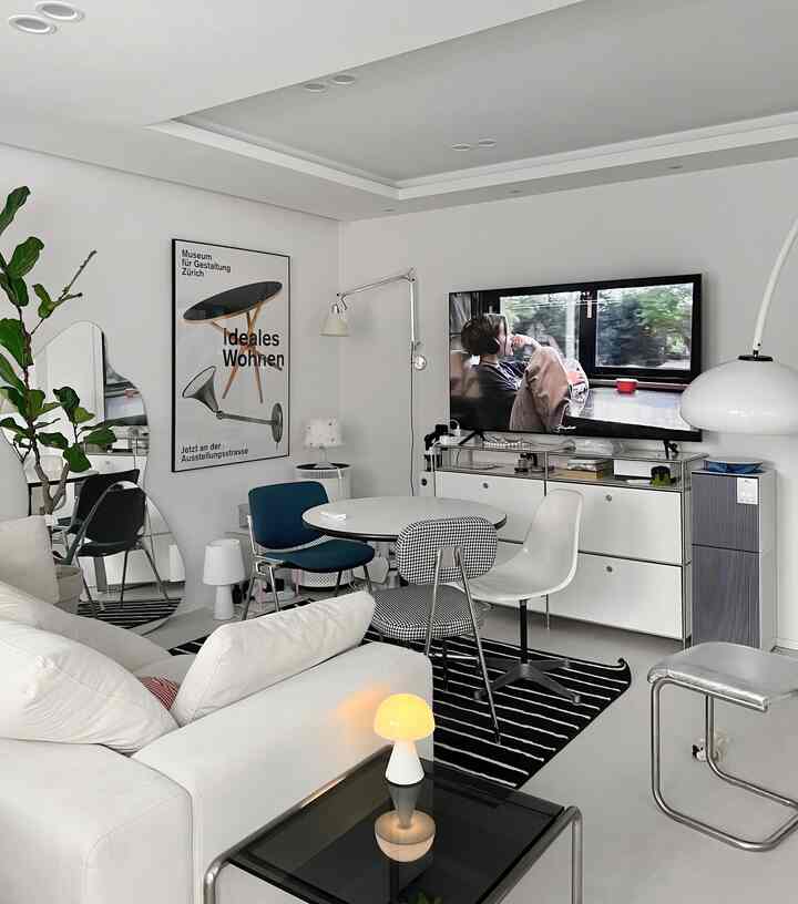 白とネイビートーンのリビングルーム、円形テーブルと多様な椅子が配置されたモダンで清潔感のあるインテリア