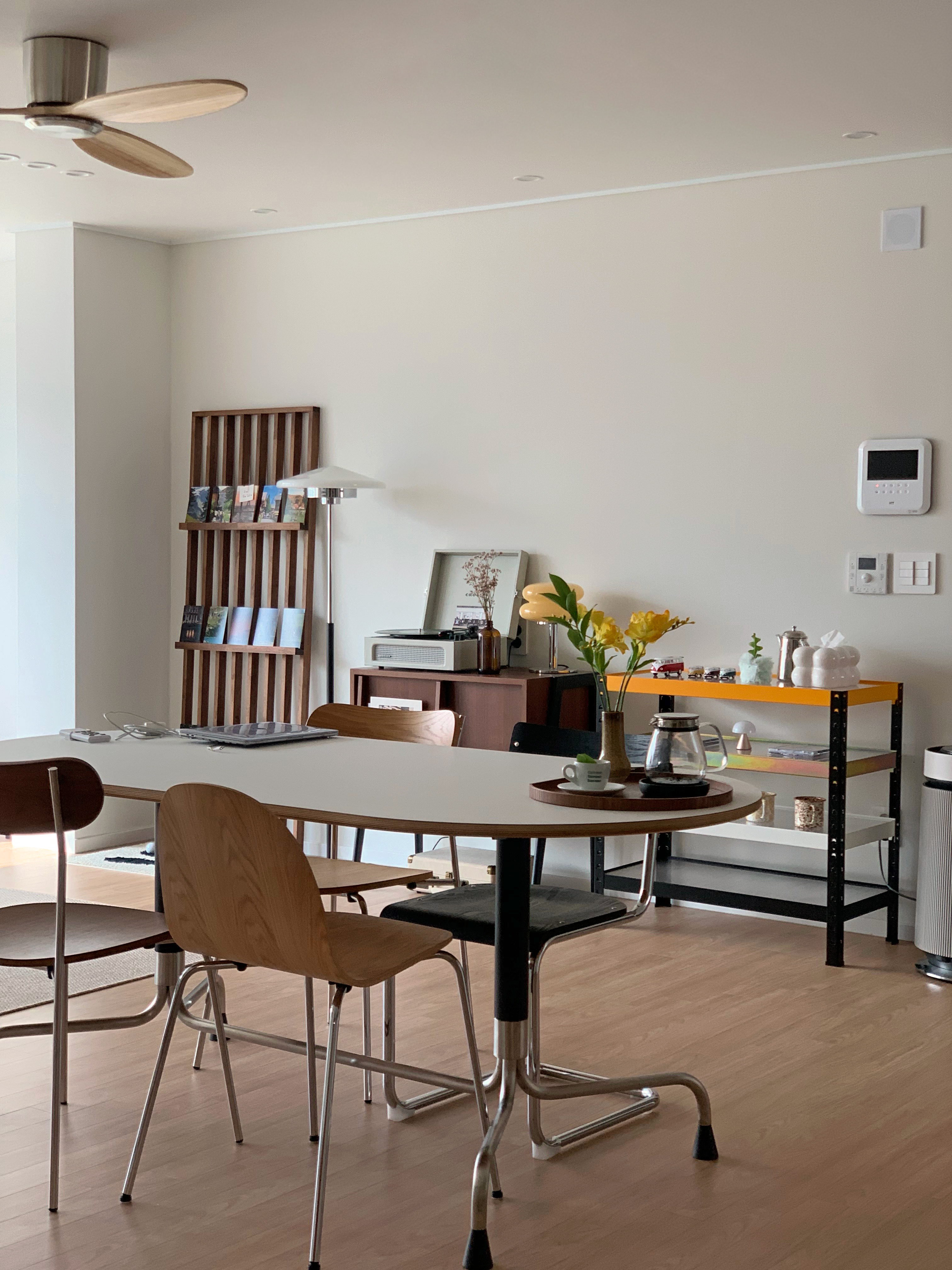 Natural-toned dining room featuring an oblique oval dining table and wood chairs with a simple, modern atmosphere