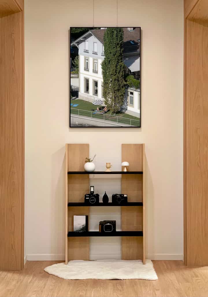 ナチュラルな木目調とミニマルなスタイルのリビング、壁のアートと木製棚が調和した印象的な空間