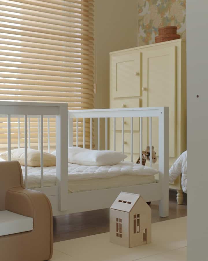 Beige and wood tone kids' room featuring white children's bed and toy storage creating a cozy atmosphere