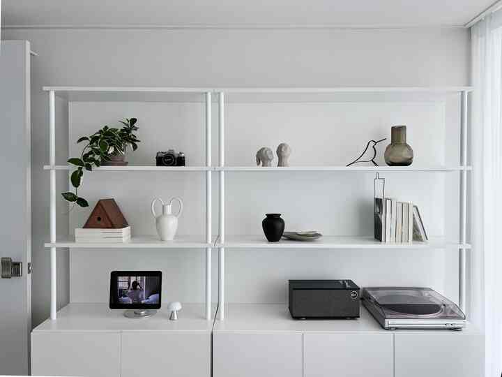 Simple modern space featuring white and natural-tone bookshelf with decorative objects