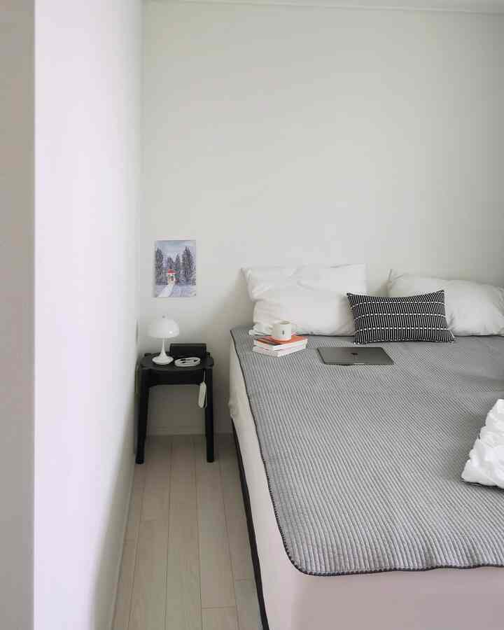 明るいグレーのベッドパッドを配した、白い壁とナイトスタンドのあるシンプルでモダンな寝室の雰囲気のあるインテリア