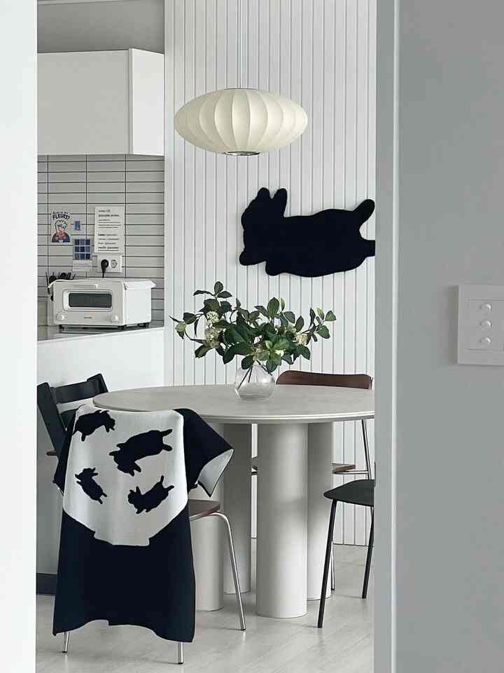 White and black toned dining room featuring a round dining table and pendant light with a clean modern interior