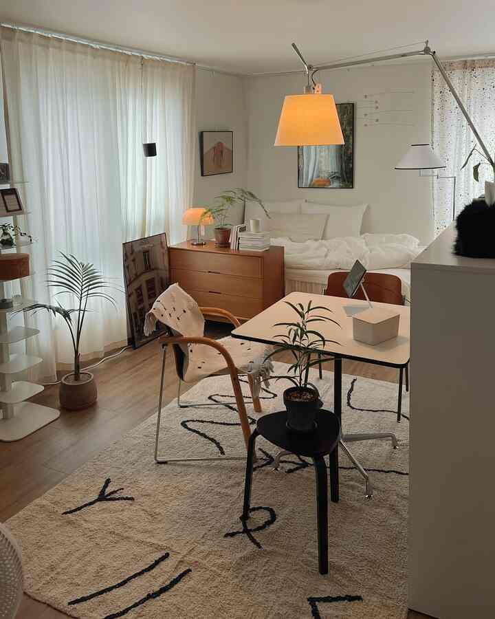 Natural tone bedroom featuring white curtains, wooden furniture, and plants creating a cozy and clean atmosphere