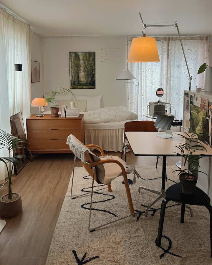 Natural-toned studio apartment featuring a bedroom and desk with warm, cozy interior atmosphere