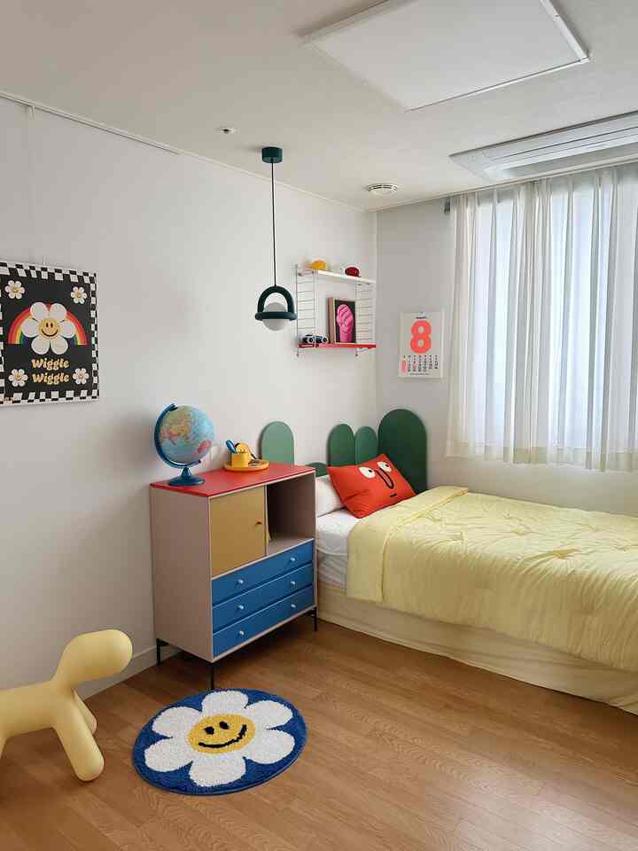ホワイトの壁とイエローのベッドがあるナチュラルカラーの子供部屋、多彩な家具とカーテンが配置された明るく暖かな雰囲気のインテリア